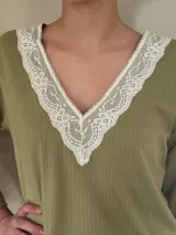Pijama verde con textura acanalada, compuesto por un top de mangas largas con escote en V con puntilla blanca y un pantalón recto con lazo blanco en la cintura.