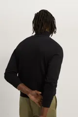 Jersey negro de punto fino con cuello alto y manga larga.
