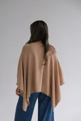Poncho de tejido de punto color beige con guarda calada en el ruedo.