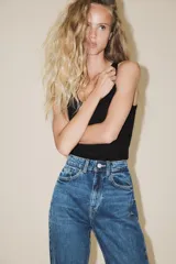 Jeans de tiro alto color negro con efecto lavado, corte mom fit, cinco bolsillos y cierre frontal con cremallera y botón metálico.