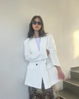 Blazer blanco con solapas de muesca, cierre cruzado con dos botones, bolsillos delanteros con solapa y corte recto.