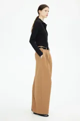Pantalón ancho color marrón claro con pinzas, bolsillos laterales y trabillas para cinturón.