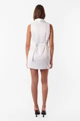 Minivestido blanco tipo blazer sin mangas, con cuello solapa, doble botonadura cruzada, bolsillos ojal y tira de ajuste en la espalda.