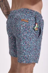 Short de baño para hombre, color azul oscuro con estampado floral o botánico en tonos rosados y celestes. Presenta cordón de ajuste blanco en la cintura.