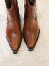Botas cortas de cuero color marrón con punta fina, taco cuadrado y apliques de tachas metálicas.