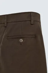 Pantalón chino color beige, de corte recto y tiro medio. Confeccionado en tejido de algodón con elasticidad, con bolsillos laterales y traseros de vivo. Cierre frontal con cremallera y botón.