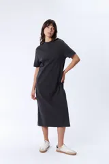 Vestido largo gris de corte recto, con cuello redondo y mangas cortas. Presenta aberturas laterales en el ruedo.