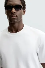Camiseta blanca de algodón interlock con elasticidad, corte recto, cuello redondo y mangas cortas.