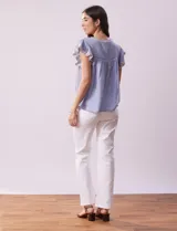 Blusa blanca de algodón con cuello a la base y escote en V con lazo de ajuste. Tiene mangas cortas con terminación amplia y bordados en delantera, mangas y espalda.