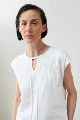 Remera de manga corta color verde agua con bordado floral blanco en la zona del pecho y cuello con abertura en forma de lágrima.