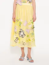 Pollera larga hasta los tobillos, confeccionada en organza color amarillo pálido. Presenta cintura elastizada y flores de tela aplicadas a mano en el delantero.