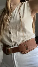 Cinto ancho de cuero vacuno color camel, con hebilla metálica dorada y detalle de costuras a mano en los bordes.