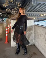 Minifalda negra de encaje con forro, con una capa de encaje más larga y asimétrica que llega hasta la pantorrilla.