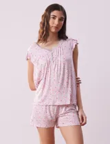 Conjunto de pijama marca René Rofé, compuesto por short y remera de tejido soft estampado con pequeñas flores rosadas. La remera tiene escote en V con aplique de puntilla gris, botones y detalle plisado. El short tiene cintura elastizada.