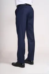 Traje de vestir azul marino, compuesto por saco de dos botones con solapa de muesca, dos bolsillos laterales con solapa y un bolsillo de ojal en el pecho, y pantalón de vestir con corte recto. Incluye camisa blanca, corbata celeste y pañuelo de bolsillo blanco con borde celeste.
