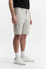 Bermuda color beige de corte chino, con presillas para cinturón y logo bordado. Confeccionada en algodón y spandex.