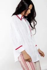 Camisa blanca de broderie con detalles en bies rojo, corte amplio y estilo relajado.