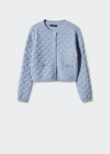 Cárdigan color crema con textura de punto, cuello redondo, cierre frontal con botones y bolsillos frontales decorativos. Corte cropped y mangas largas.