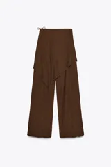 Pantalón marrón de tiro medio con cintura elástica y pierna ancha. Presenta una superposición tipo pareo ajustable con lazadas.