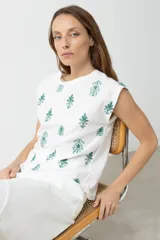 Blusa blanca de mangas cortas con bordado floral en el frente.