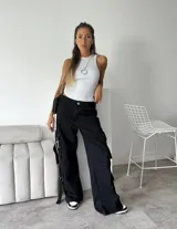 Pantalón cargo negro de denim rígido, corte wide leg, con bolsillos laterales y detalles de tiras con hebillas en los laterales.