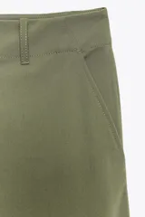 Pantalón de tiro alto color verde oliva, de corte recto y pierna ancha, con bolsillos laterales y traseros. Cierre frontal con cremallera y botón.