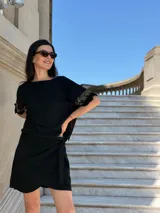 Remera negra de corte holgado con mangas cortas con volados y detalle de apliques de piedras en los volados.