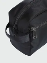 Neceser rectangular de viaje de color negro, con textura de tejido acanalado en diagonal y el logo "BOSS" en relieve en la parte superior. Posee cierre de cremallera y una correa lateral para transporte.