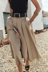 Vestido midi con cuerpo negro sin mangas y falda plisada color beige. Incluye cinturón negro con hebilla rectangular.