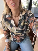 Sweater de mangas largas con cuello polo y estampado camuflado en tonos marrones, grises y beige.