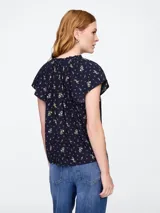 Blusa blanca de manga corta con escote en V y detalle de volados en el cuello.