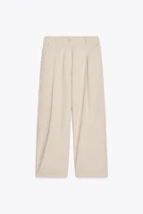 Pantalón color beige de tiro alto, corte ancho y largo midi, con pinzas delanteras, bolsillos laterales y traseros. Cierre frontal con cremallera y botón.