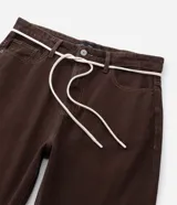 Pantalón masculino negro de corte baggy, confeccionado en sarga de algodón. Presenta detalles de costura, cierre tradicional de botón y cremallera, y un cordón blanco para ajustar la cintura.
