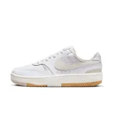 Championes urbanos Nike Gamma Force de mujer, color blanco con detalles en beige y suela con detalles en color caramelo. Presentan el logo de Nike en beige en los laterales.
