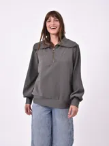 Buzo gris con cierre de cremallera en el cuello, de mangas largas y diseño holgado.