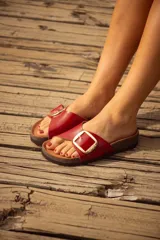 Sandalias rojas con base de corcho y hebilla dorada con el logo de la marca.