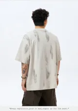 Remera de manga corta color nude con efecto tie-dye o goteo en tonos grises y blancos. Presenta un estampado gráfico frontal con tipografía estilo metal/rock, el texto "RETROGRADES", y el número "06" en verde menta.