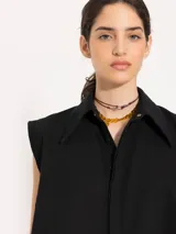 Camisa negra corta sin mangas, de corte recto y cuello clásico.