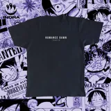 Remera negra con estampado de viñetas del manga One Piece, con el título "Romance Dawn" y el logo de la marca Indra.