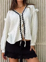 Camisa blanca con lunares negros, escote en V con volados y lazos para atar.