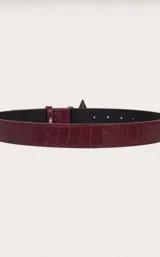 Cinturón color borgoña con textura símil cuero de cocodrilo y hebilla metálica con forma de estrella.