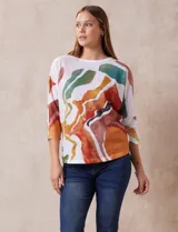 Buzo blanco con estampado abstracto en tonos naranja, verde, marrón y rojo. Tiene cuello redondo y mangas 3/4.