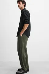 Pantalón verde oscuro con textura de rayas verticales, corte relaxed fit, cintura elástica ajustable con cordón, bolsillos delanteros y bolsillo trasero de parche.