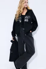 Campera negra con capucha y cierre frontal, con bolsillo tipo canguro y estampado blanco con la inscripción 'Seine Paris'.