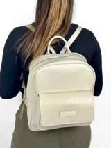 Mochila de cuero color crema con bolsillo frontal con textura de piel de cocodrilo.