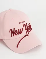 Gorra de béisbol color rosa claro con bordado en relieve de la inscripción "New York" en color borgoña.