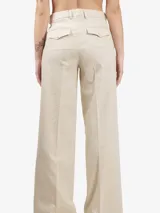 Pantalón palazzo color beige con rayas verticales plateadas y aplicaciones de pedrería. Tiene trabillas, cierre de botón, bolsillos laterales y solapas en la espalda.