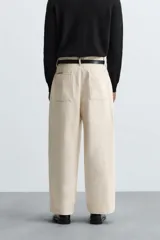 Pantalón negro de corte amplio, tipo balloon fit, con pinzas en la cintura, bolsillos laterales y traseros de ojal.