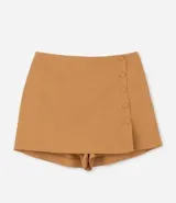 Short pollera color ocre con corte sastrero, botones delanteros forrados y pequeña abertura en la pierna.