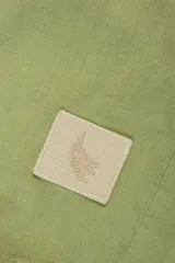 Camisa de manga larga color verde claro, confeccionada en tejido de lino y viscosa, con botones de madera y parche con logo.